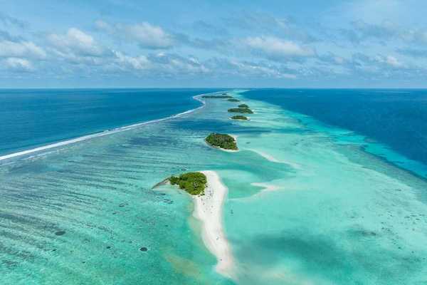 A chain of islands uninhabited in Tha Atoll Maldives. Green islands against turqoise sea.