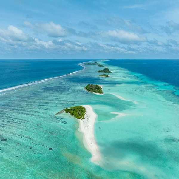 A chain of islands uninhabited in Tha Atoll Maldives. Green islands against turqoise sea.