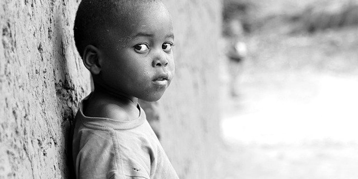 A child leans against an earthen wall