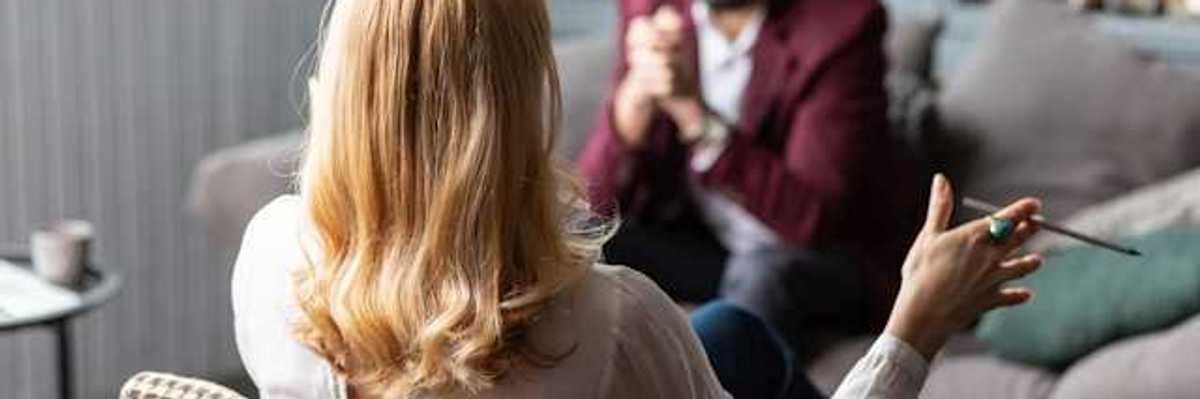 A client sitting on a sofa facing a female therapist