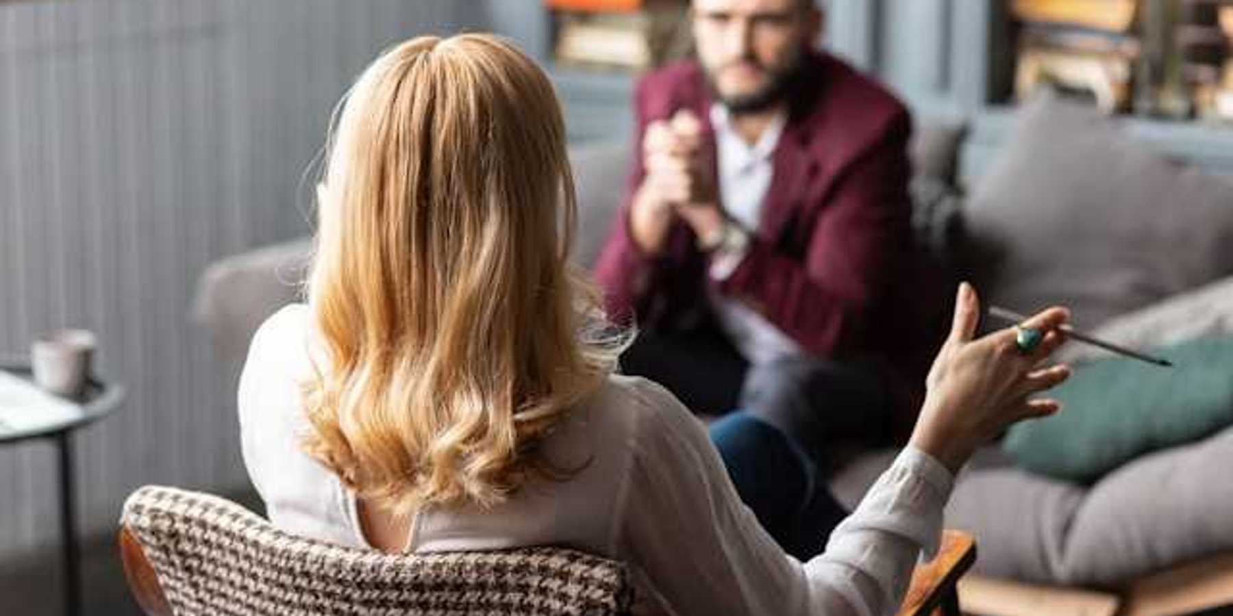 A client sitting on a sofa facing a female therapist