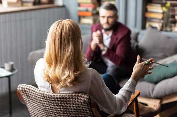 A client sitting on a sofa facing a female therapist