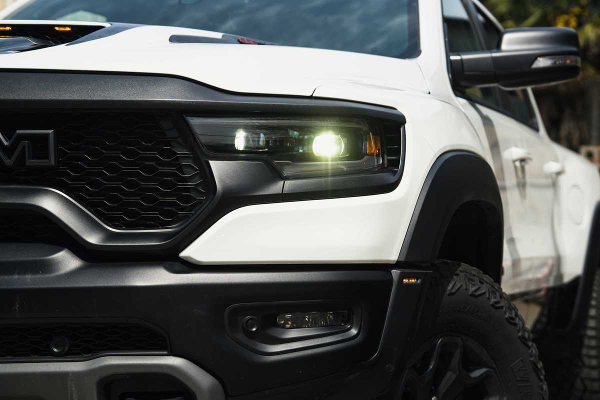 a close up of front of a heavy duty white truck with its lights on.