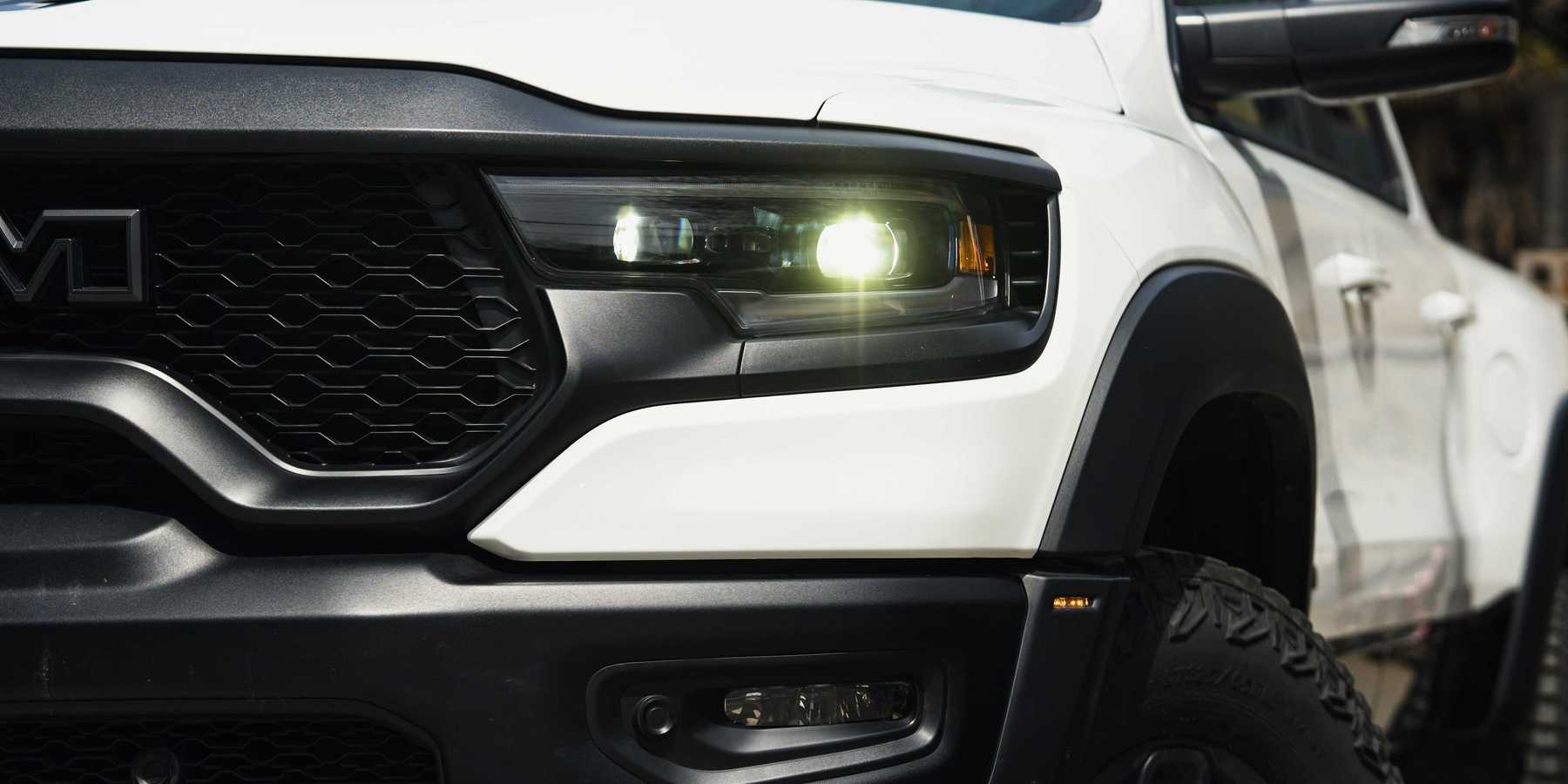 a close up of front of a heavy duty white truck with its lights on.