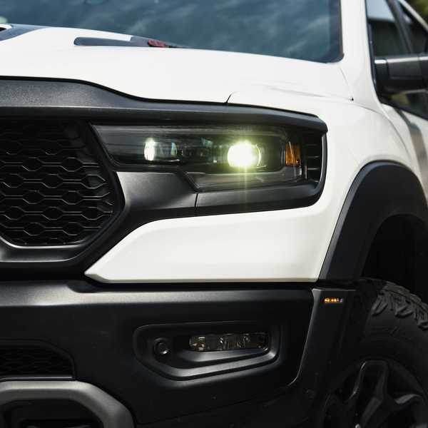 a close up of front of a heavy duty white truck with its lights on.