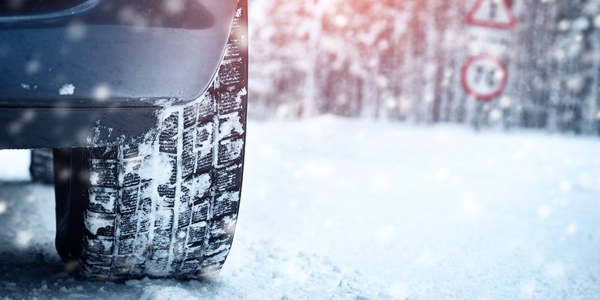 A closeup of a car tire on a snowy road.