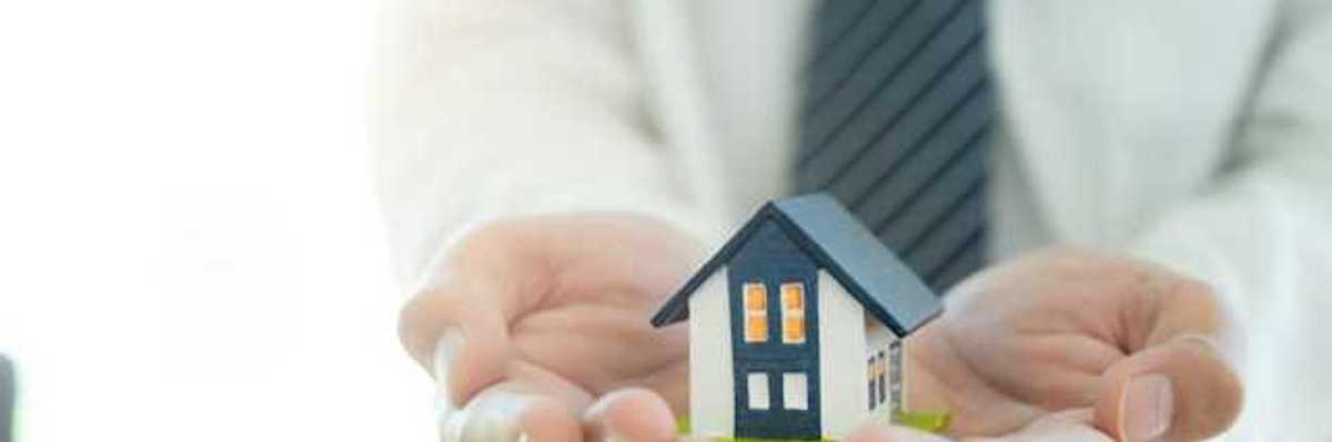 A closeup of a person's hands holding a miniature model of a house