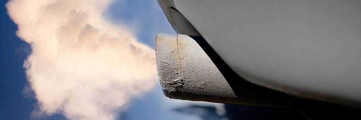 A closeup of a tailpipe with smoke coming out of it