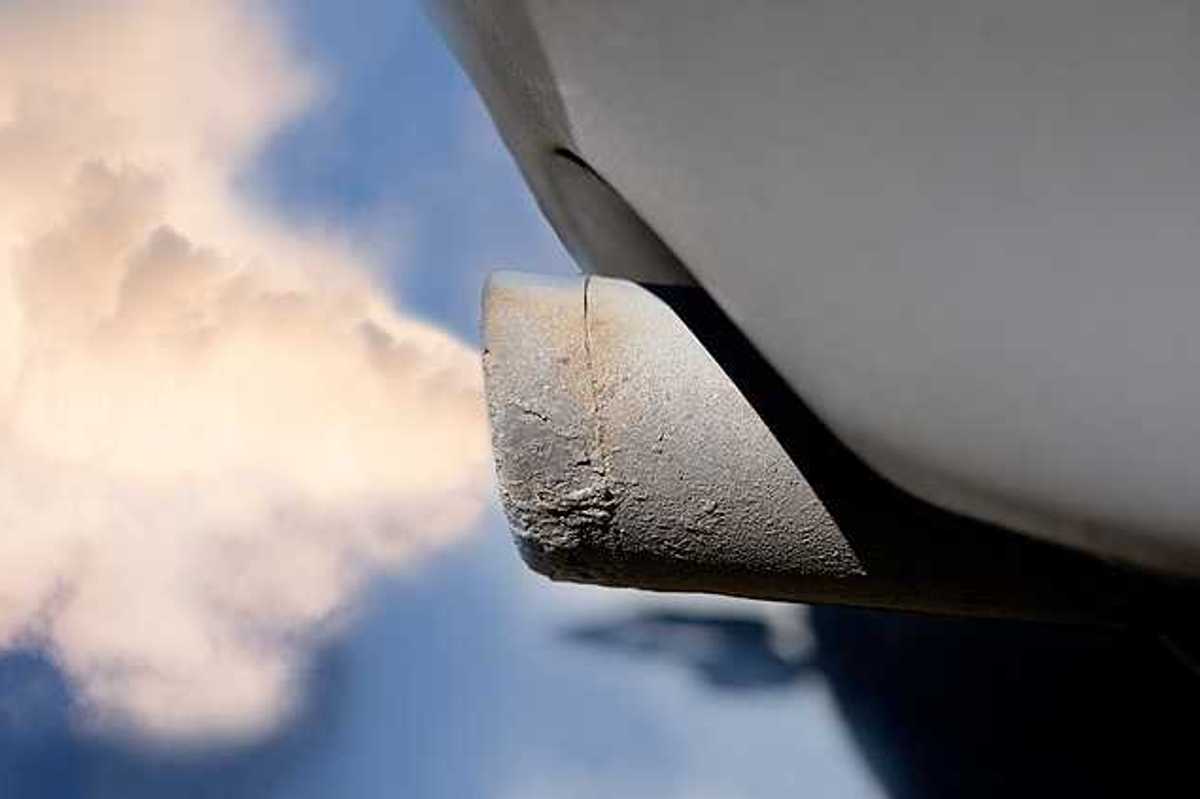 A closeup of a tailpipe with smoke coming out of it