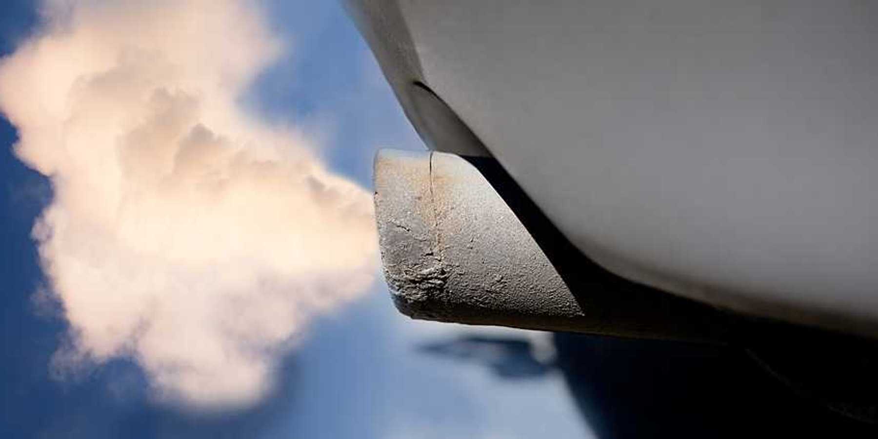A closeup of a tailpipe with smoke coming out of it