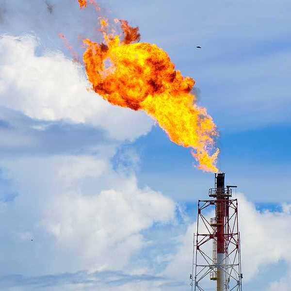 A closeup view of a gas tower flaring flames into the sky