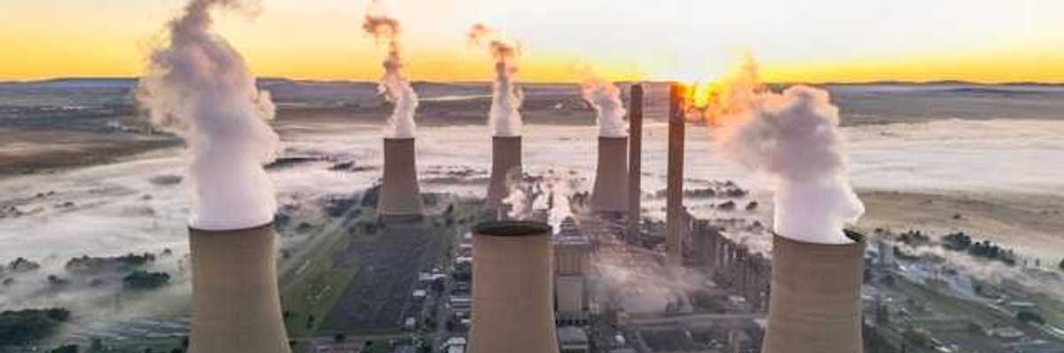 A coal plant viewed from above with smoke emitting from towers