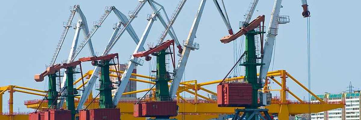 A coal terminal with cranes and piles of coal next to a body of water