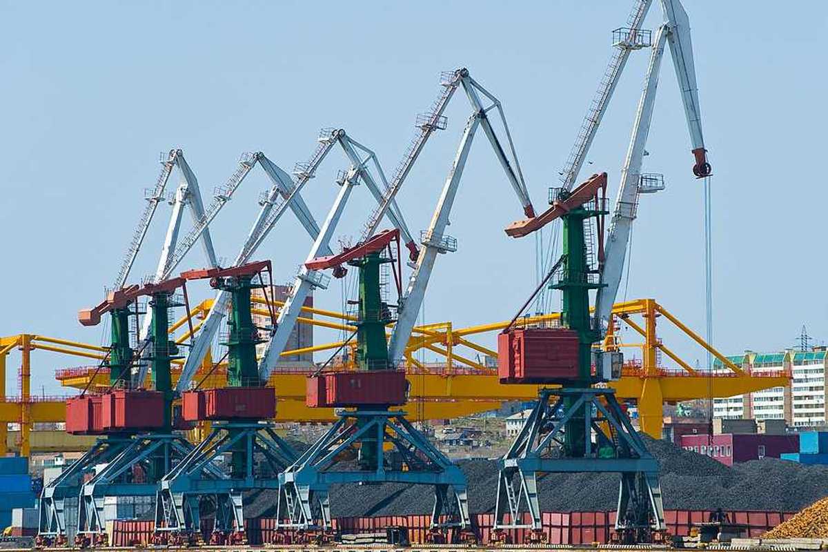 A coal terminal with cranes and piles of coal next to a body of water