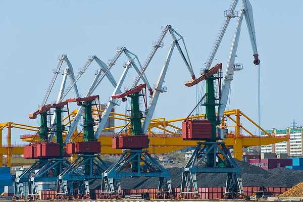A coal terminal with cranes and piles of coal next to a body of water