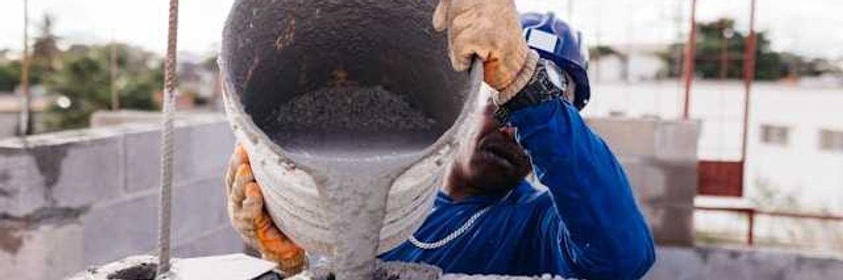 A construction worker pouring cement into open bricks