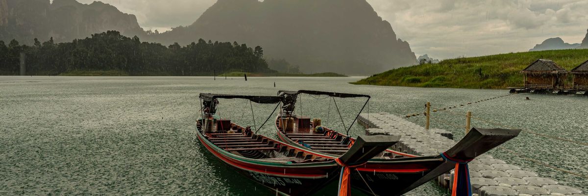 A couple of boats sitting in the water as a storm approaches