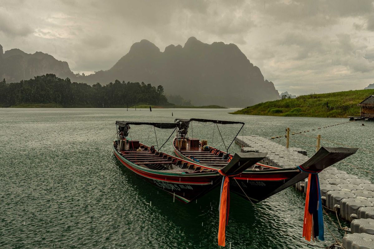 A couple of boats sitting in the water as a storm approaches