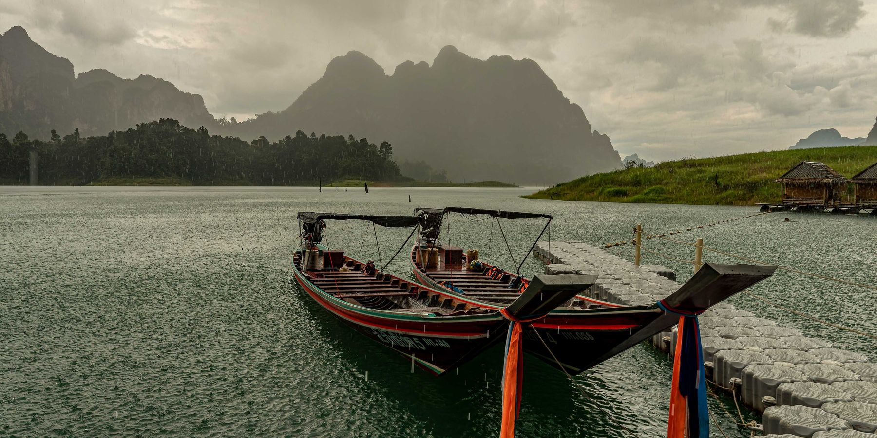 A couple of boats sitting in the water as a storm approaches