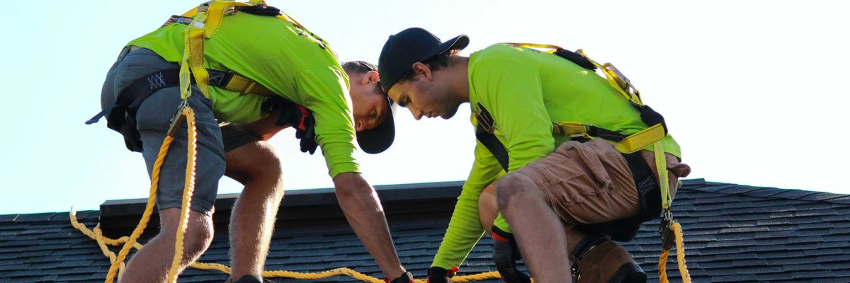 a couple of men working on a roof