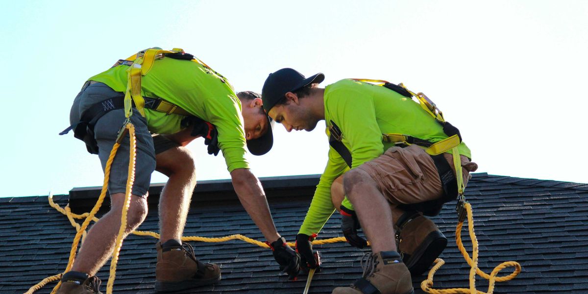 a couple of men working on a roof