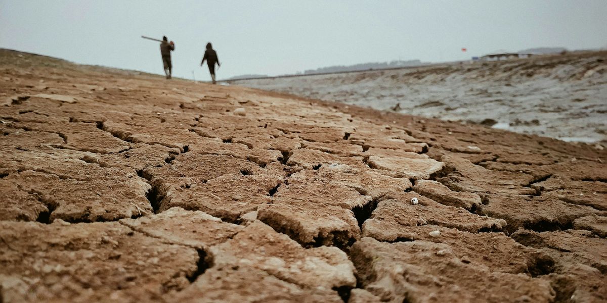 a couple of people walking across a dry field