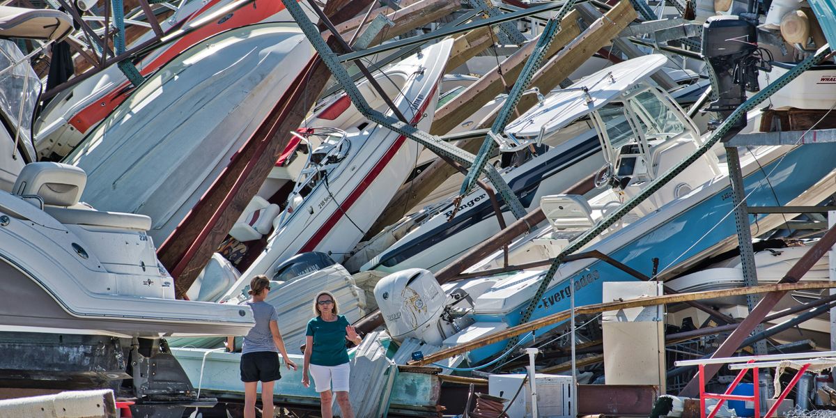 a couple of women standing next to a pile of boats.