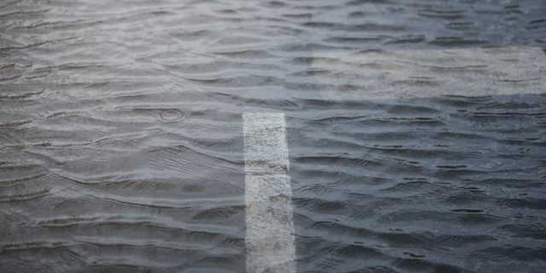 A cross in the road is reflected in a puddle of water