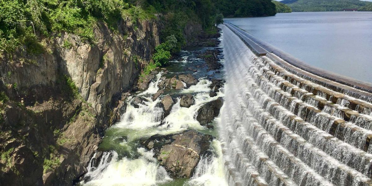 A dam and reservoir with water spilling into a river below.