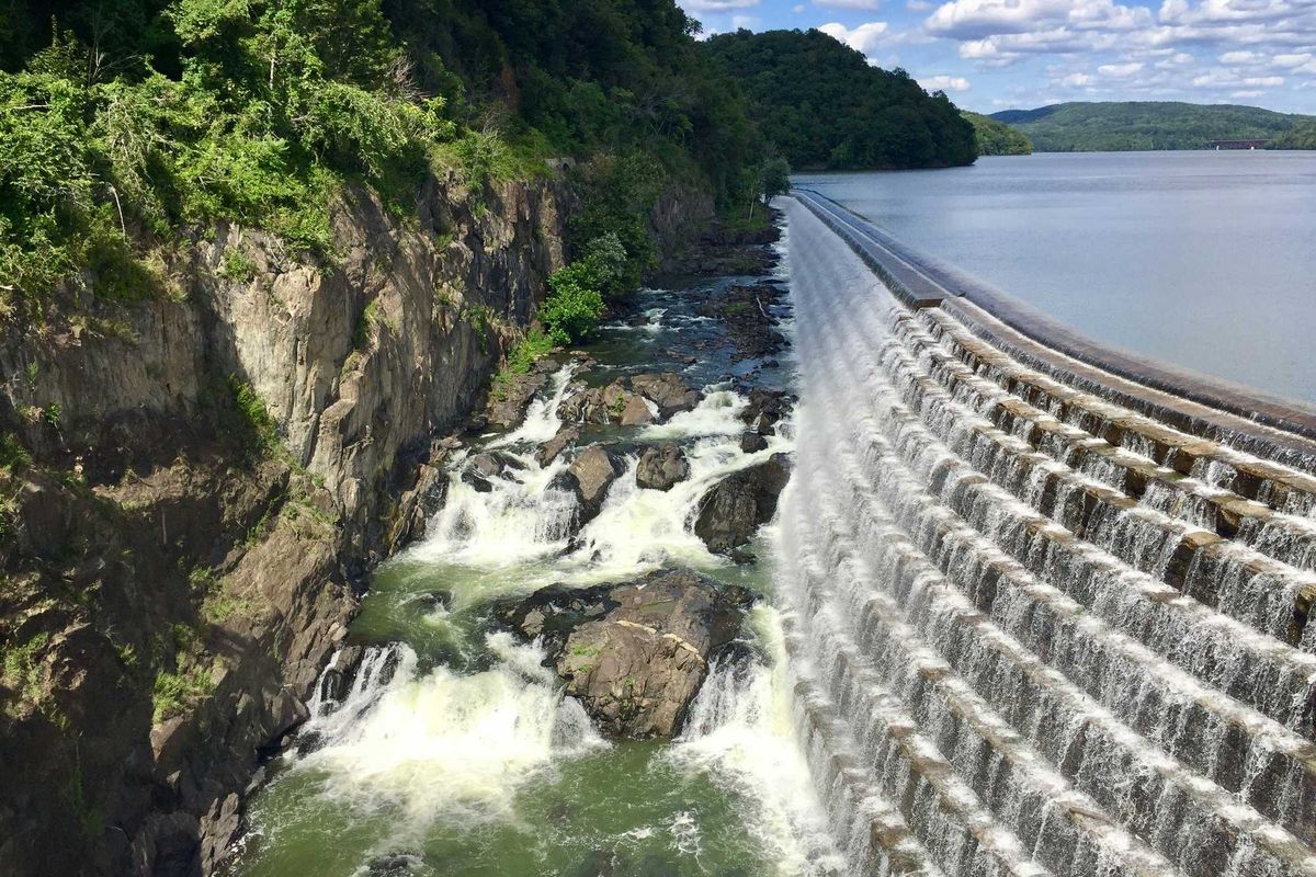 A dam and reservoir with water spilling into a river below.