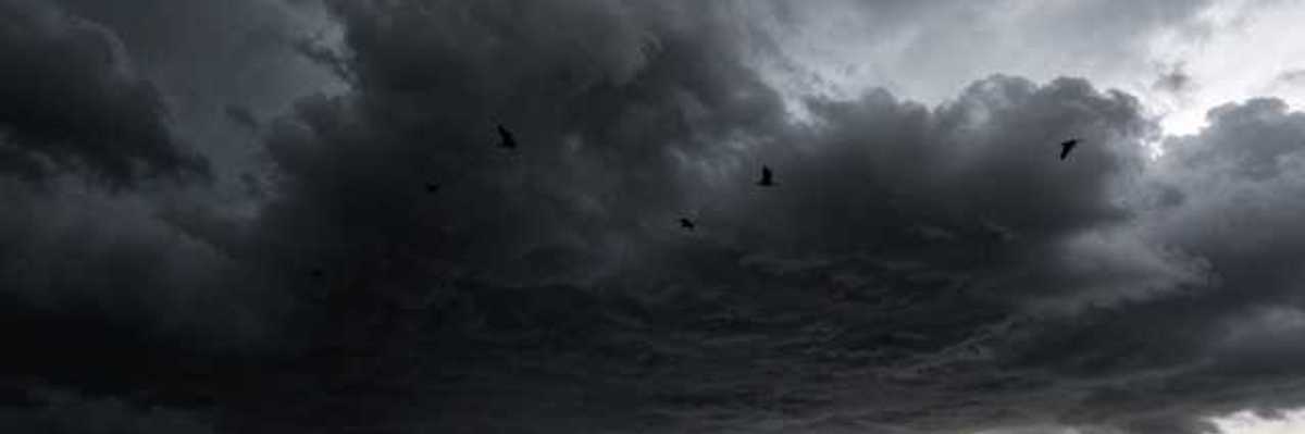 A dark storm cloud with rain in the distance