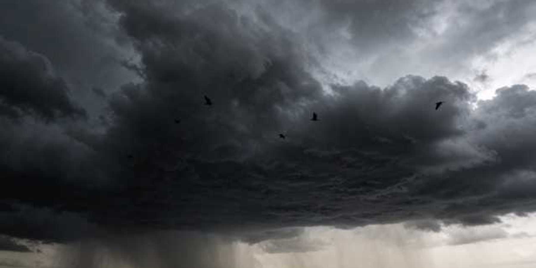 A dark storm cloud with rain in the distance