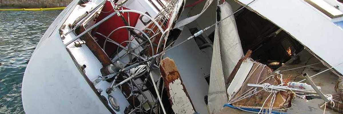 A destroyed boat leaning against a dock after a hurricane