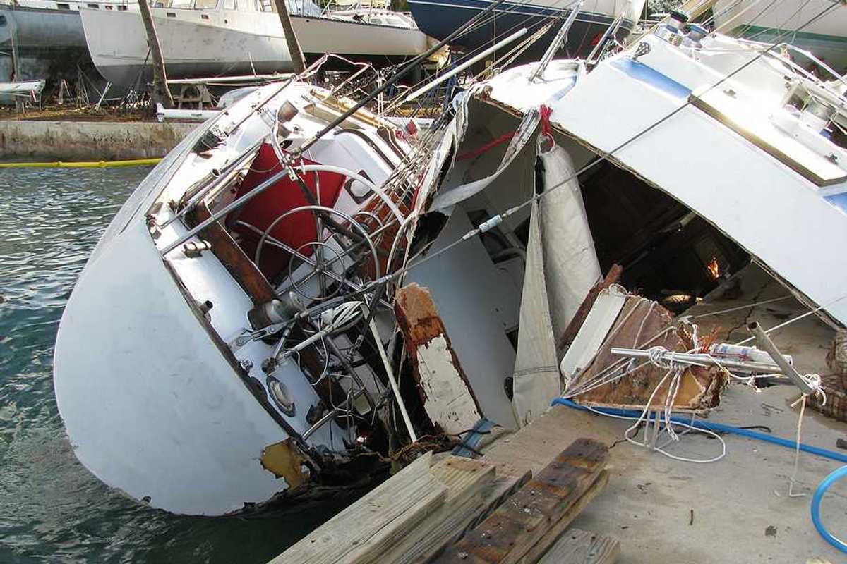 A destroyed boat leaning against a dock after a hurricane