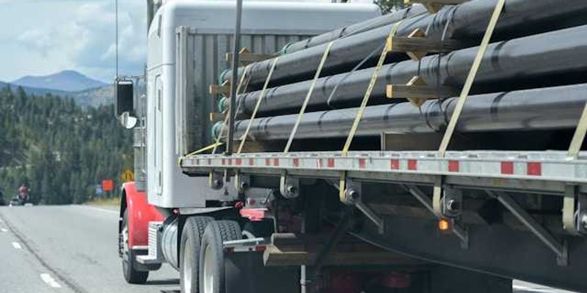 A diesel truck carrying pipeline parts along a highway