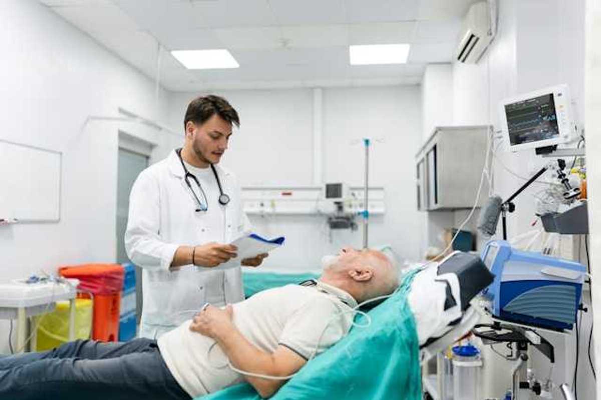 A doctor standing over a patient in an emergency room bed