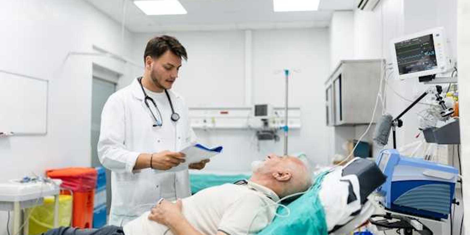 A doctor standing over a patient in an emergency room bed