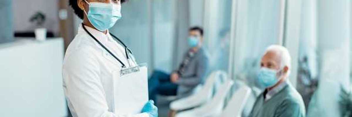 A doctor wearing a medical mask standing in front of patients in chairs