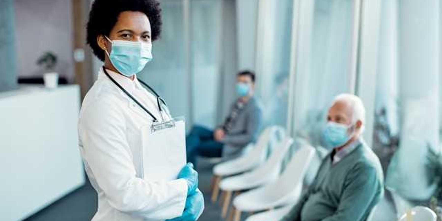 A doctor wearing a medical mask standing in front of patients in chairs