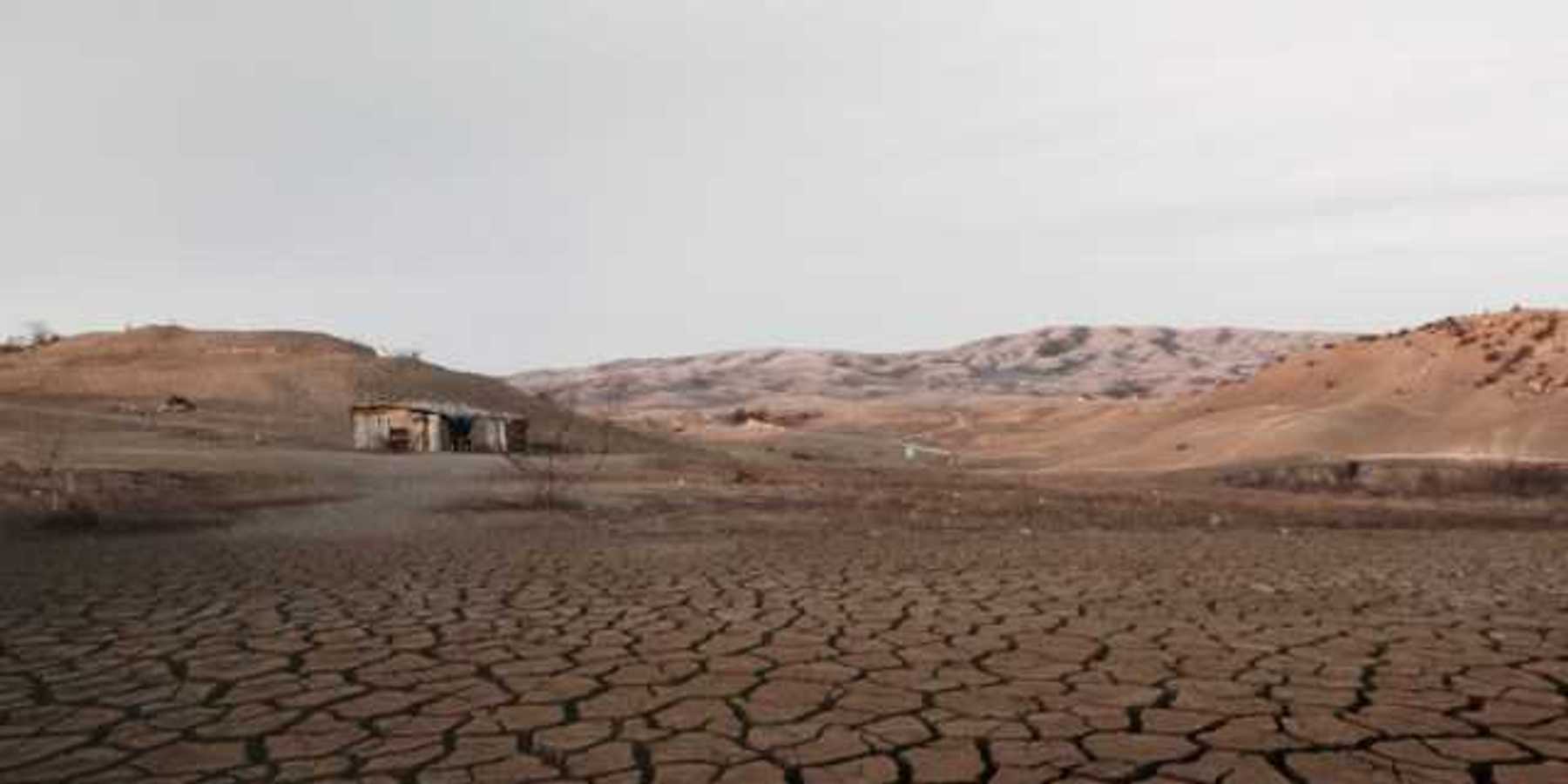 A dried up lakebed with a shack at one end