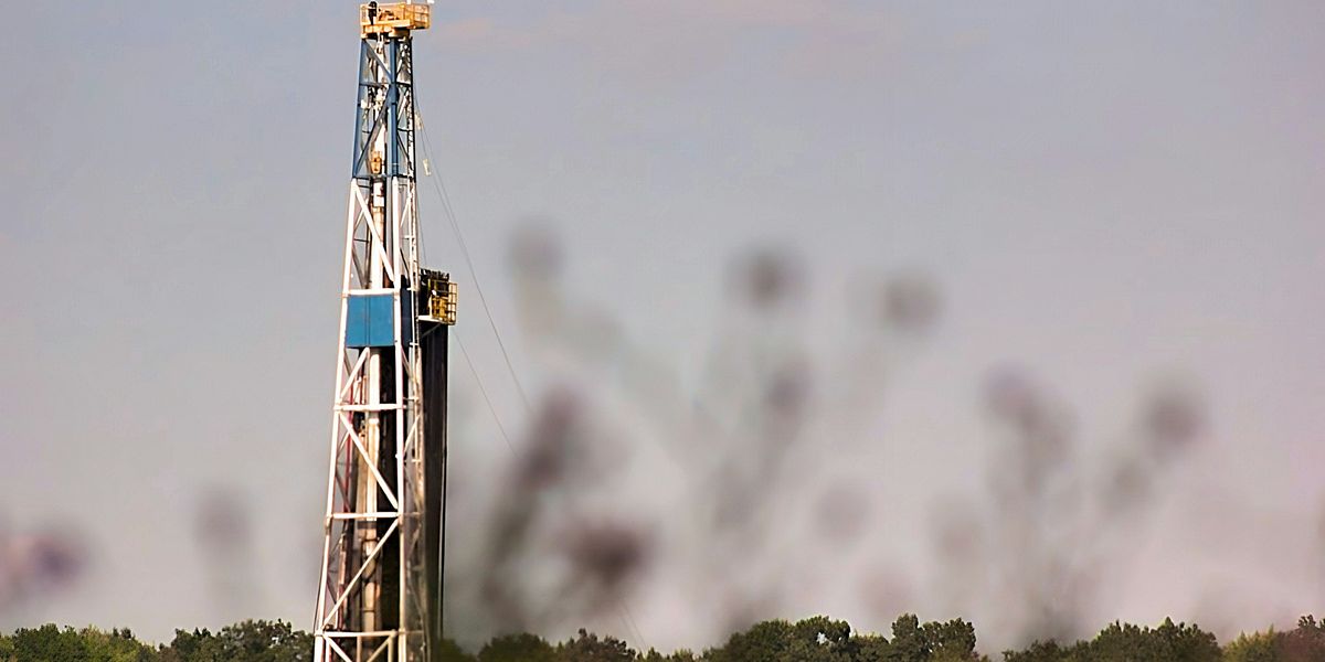 A drilling rig in a field with trees in the background.