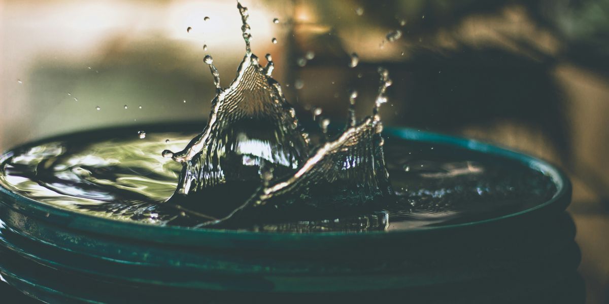 A drop of water falling into a bucket of water.