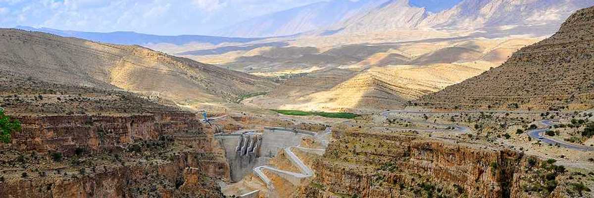 A dry environment with a dam and a small amount of water in view