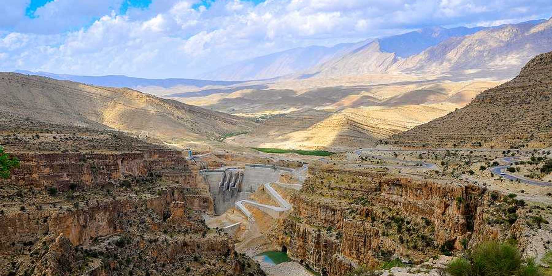 A dry environment with a dam and a small amount of water in view