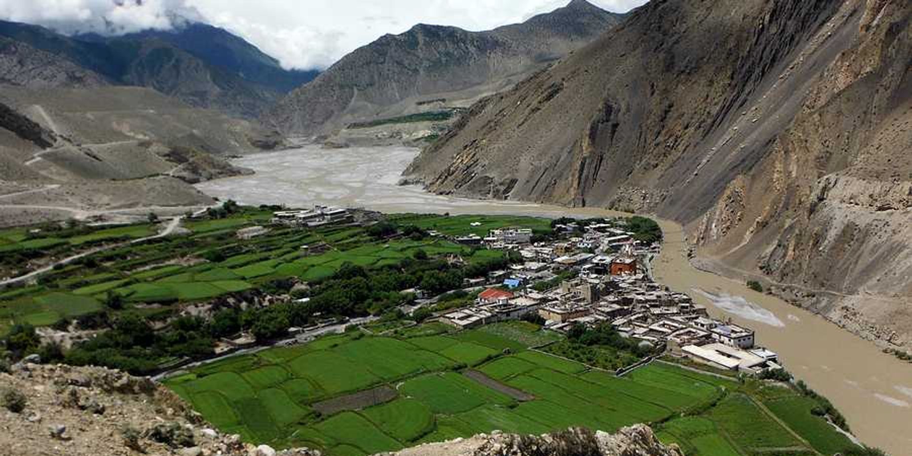 A dry river valley with a town surrounded by green fields
