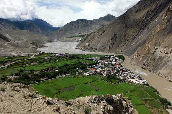 A dry river valley with a town surrounded by green fields