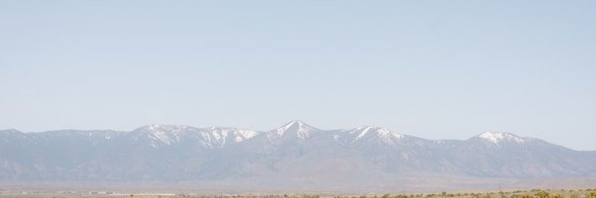 A dry scrubby environment with snow-capped mountains in the background