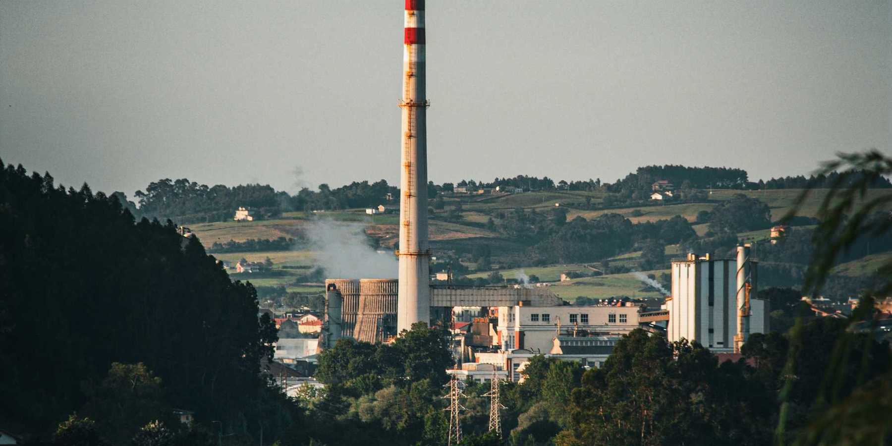 A factory or coal power plant with a smoke stack in the distance.