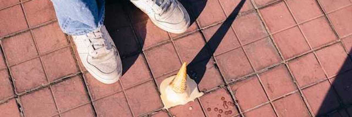 A fallen ice cream cone melting on the sidewalk