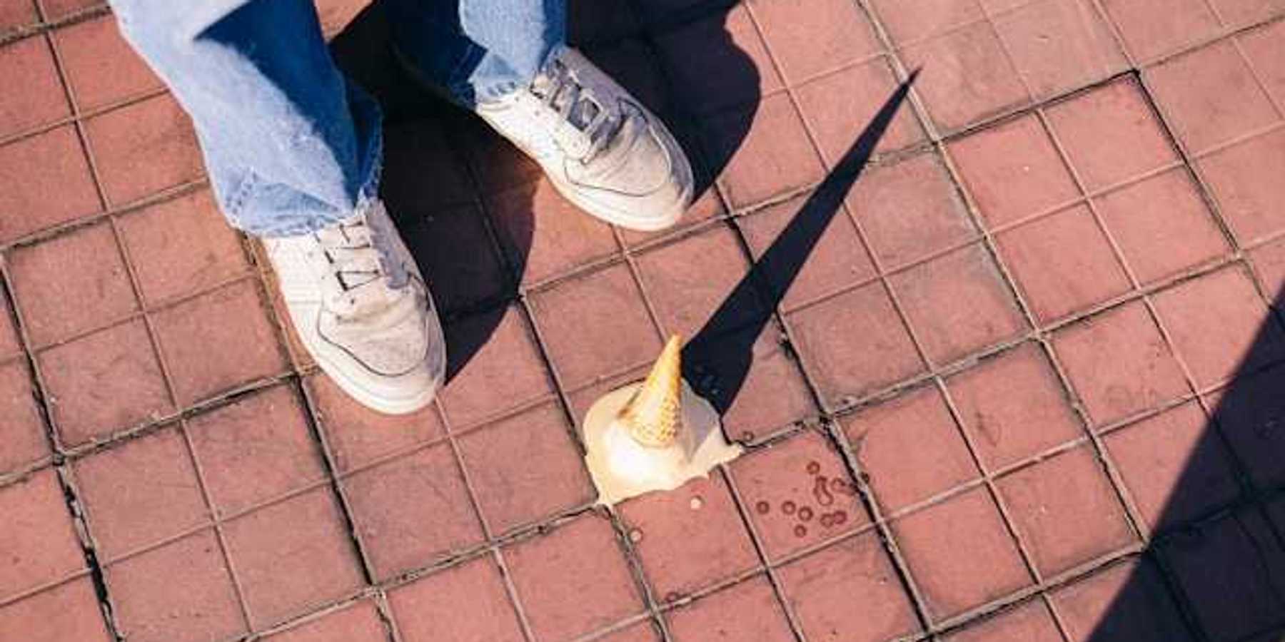 A fallen ice cream cone melting on the sidewalk